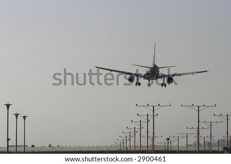 Image of a jet plane landing with landing gears down from behind