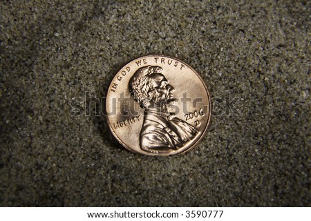 Close up / macro of a US penny in sand, heads side up.
