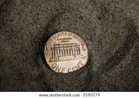 Close up / macro of a US penny in sand, tails side up.