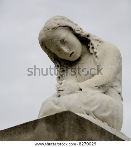 Statue of a crying girl atop a tomb in an historic New Orelans cemetery