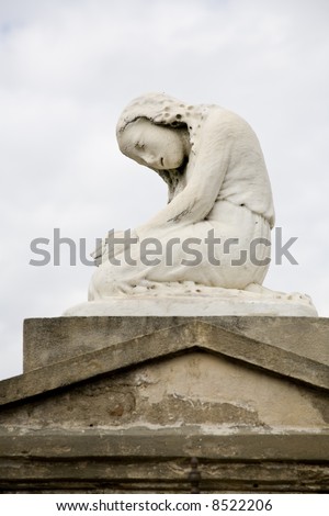Statue of a crying girl atop a tomb in an historic New Orleans cemetery
