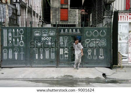 A gate to a hardware store in Makati, Philippines with a man exiting.