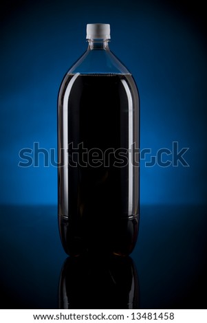 Vertical low key image of a bottle of dark soda with a reflective surface and blue separation light.