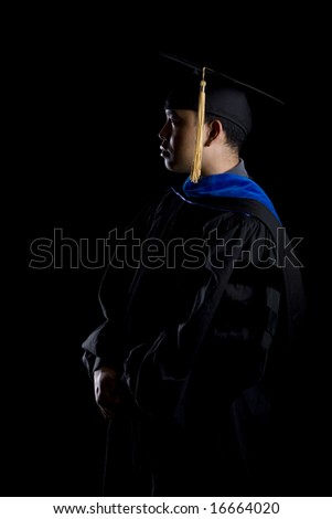 Low key image of a male model in graduation robes and regalia