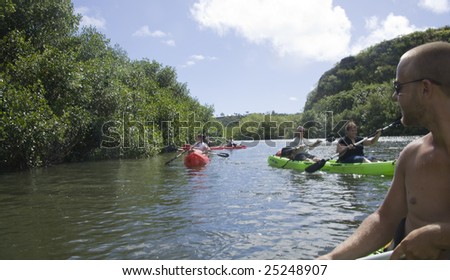 KAUAI, HI - JULY 25: Kayak tour by Outfitters Kauai up a gentle river with tour guide in the foreground, July 25th, 2008 in Kauai.