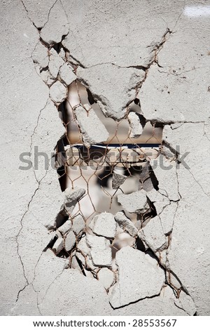 Vertical image of a broken wall showing the studs and chicken wire.