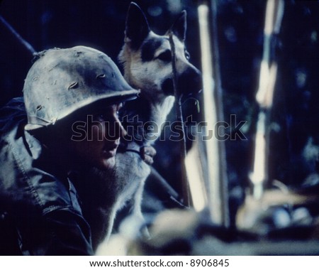A U.S. Army military police soldier patrols the wire at a fire base with a German Shepard.