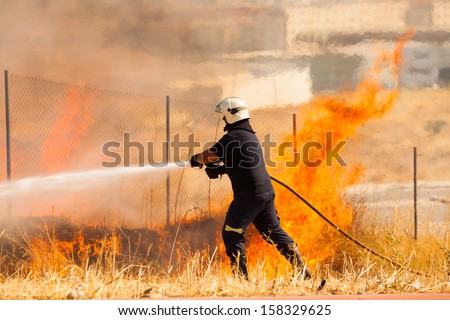 A firefighter extinguish a fire in the forest with a water hose