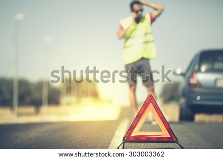 Emergency triangle with man and car in the background.