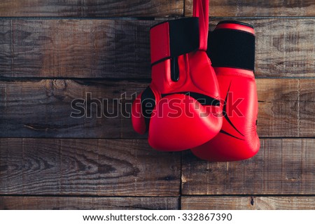 Pair of boxing gloves hanging in a rustic wooden wall. Vintage tone.