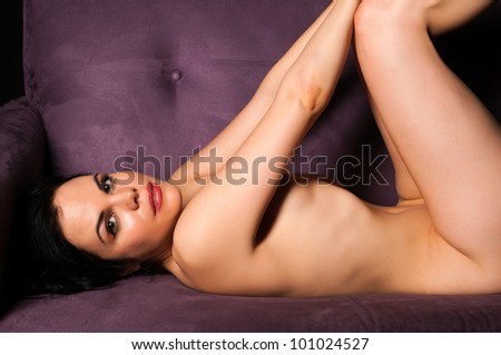 Pretty slender brunette nude on a purple couch