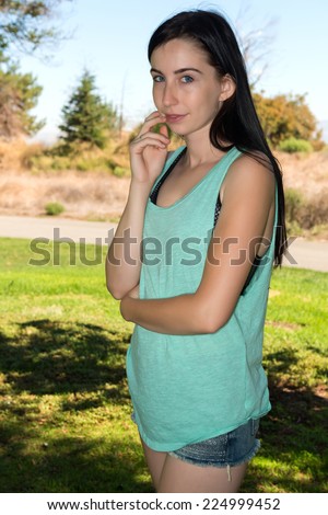 Pretty young brunette in a teal tee shirt and denim shorts