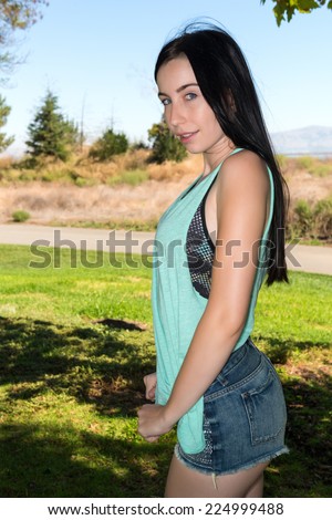 Pretty young brunette in a teal tee shirt and denim shorts