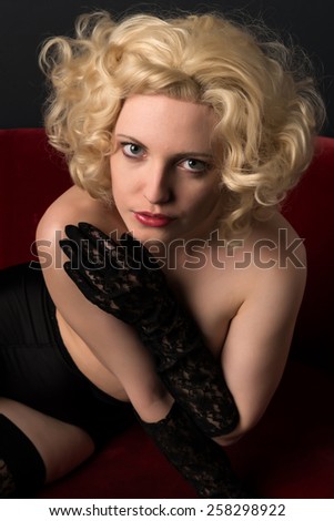 Pale blonde on a red couch topless in black