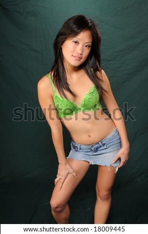 Pretty young Vietnamese girl in a green bikini top and jeans skirt
