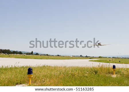 Single engine airplane flying low over a runway, South County Airport, San Martin, California