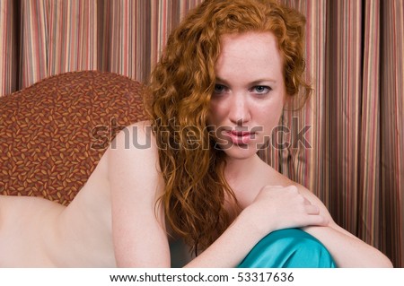 stock photo Pretty pale redhead posing nude on an overstuffed chair