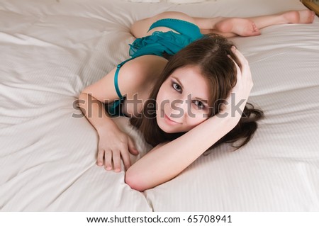Slender young brunette in bed in teal lingerie