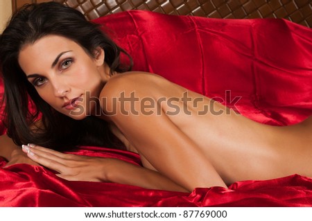 Beautiful slender brunette lying nude in bed