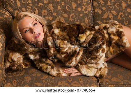 Pretty blonde lying nude in a fur coat