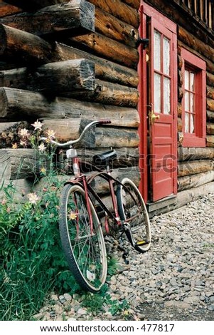 Vintage Cruiser Bicycle leaning against a log cabin