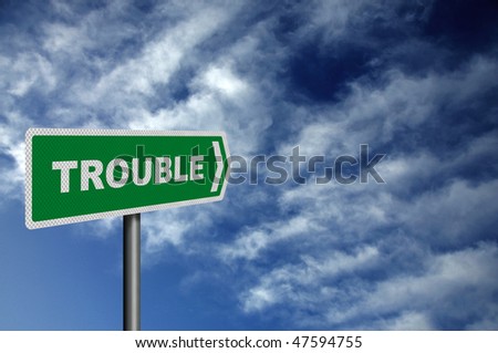 Photo realistic metallic reflective 'Trouble Ahead' road sign, against a dark, stormy sky. With space for your text overlay / editorial