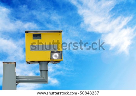 A traffic speed monitoring camera, against a bright blue sky. With space for your text / editorial overlay