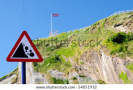 \'Beware falling rocks\' sign with steep cliffs in the background