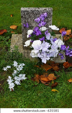 Purple and white flowers on a grave, Batsford church, Gloucestershire, England, uk