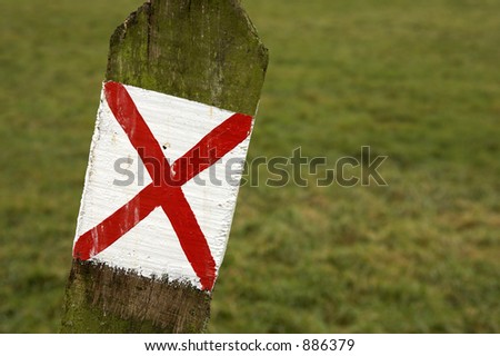 Wooden post with a red cross on