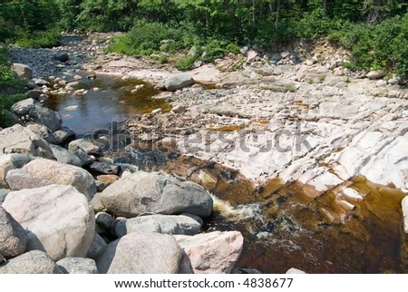 Crystal clear river flowing over the rocky landscape of Cape Breton, Nova Scotia, Canada.