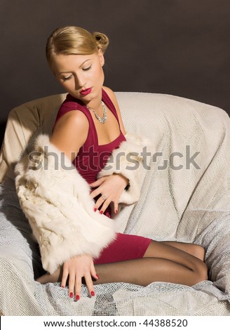 beauty blond woman in red dress and fur in chair
