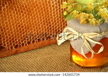 jar of fresh and delicious honey with linden flowers and honeycomb