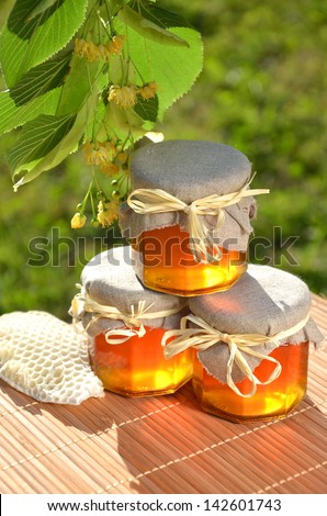 jars of fresh and delicious honey with linden flowers and honeycomb