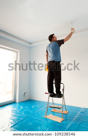 Man painting ceiling of new apartment