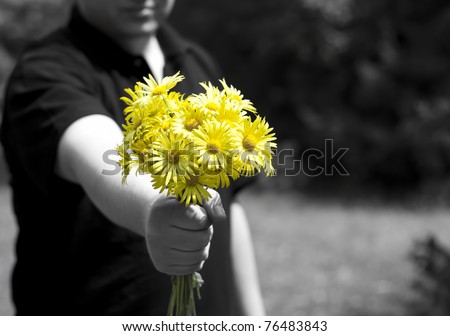 Man giving a present with yellow daisy flowers. Focus on flowers.