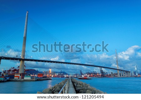 Port warehouse with containers and industrial cargoes , view under bridge on water break at sunset