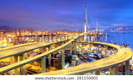 Container Cargo freight ship with working crane bridge in shipyard under Stonecutters highway bridge at sunset for Logistic Import Export, Hong kong
