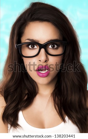 A beautiful woman with a surprised expression wearing glasses on a blue background. Surprised woman.