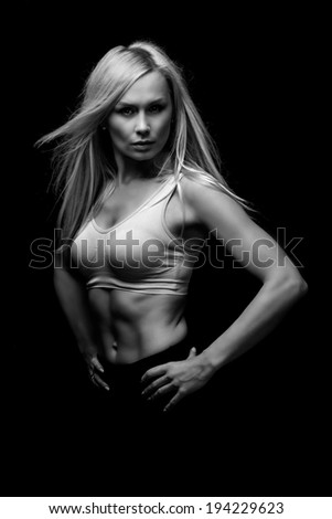 Fitness woman. Black and white image of a beautiful fit blond woman over a black background.