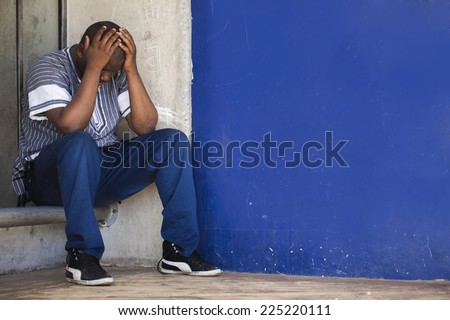 Black South African man sitting in a corner to depict depression and stress that men are suffering from in Africa.