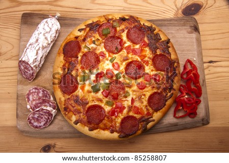 Home made Italian pizza with salami and peppers on a wooden board. Italian pizza and salami.