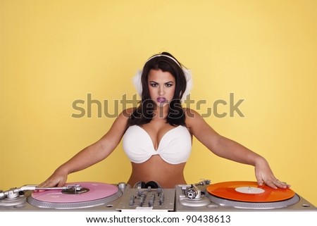 Sexy female DJ wearing a white bikini top as she plays colourful records. Sexy female DJ.