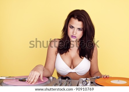 Sexy female DJ. Sexy female DJ wearing a white bikini top as she plays colourful records.