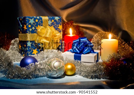 New Year (Christmas) still life with gift boxes, two candles,  sky blue satin and Christmas-tree decorations