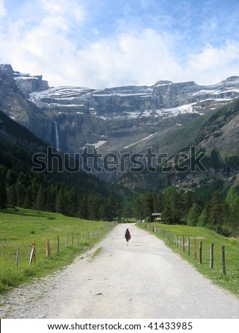 Single person on road walking towards a waterfall in Cirque de Gavarnie