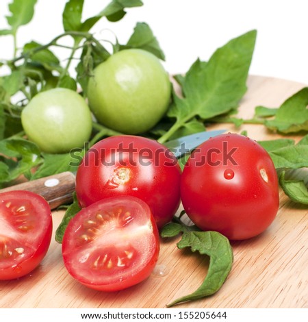 Red and green tomatoes on a kitchen chopping board, square image