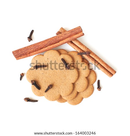 Top view of gingerbread cookies, cloves and cinnamon sticks over white background