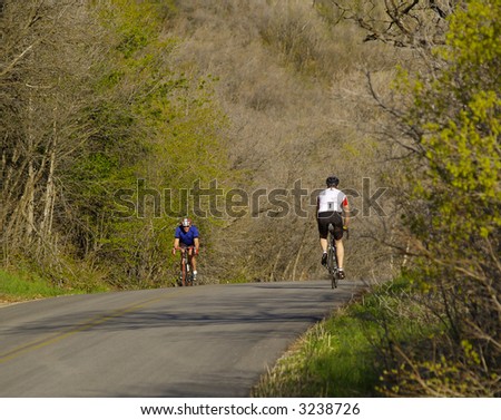 Two bicycle riders passing on a rural road at sunset
