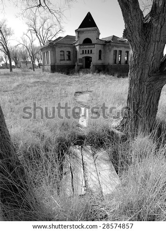 Black and white of abandoned old public school building and yard